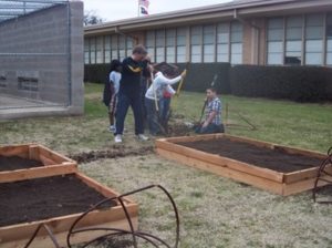 Man preparing raised garden beds with students