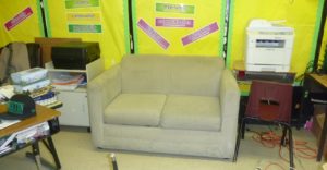Classroom reading area with a bud bug infested love seat in the center of the image