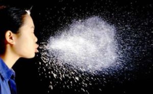 Image of woman sneezing viewer sees all the droplets in the air