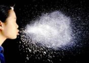 Image of woman sneezing viewer sees all the droplets in the air